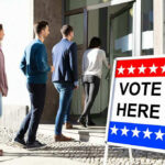 Red State Shock Upends 2026 Election Map People entering building with Vote Here sign nearby.