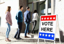 Red State Shock Upends 2026 Election Map People entering building with Vote Here sign nearby.