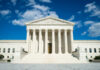 Supreme Court building with grand columns and steps under a blue sky