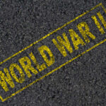 The words 'WORLD WAR II' printed in yellow on a dark asphalt surface
