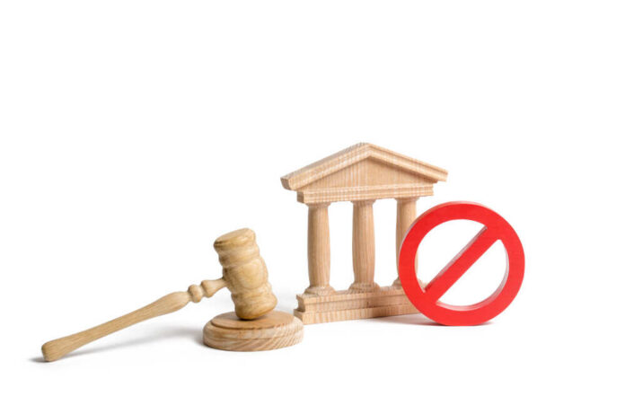 Government,Or,Bank,Building,And,A,Red,No,Symbol,With Wooden gavel, courthouse model, and red prohibition sign on white background