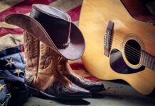 Cowboy boots and hat with guitar and flag.