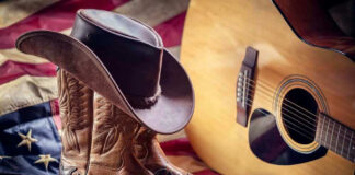 Cowboy boots and hat with guitar and flag.