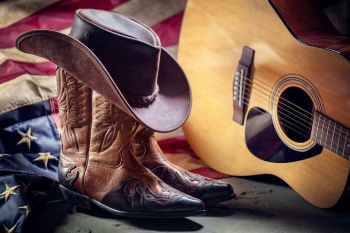 Cowboy boots and hat with guitar and flag.