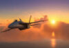 Fighter jet flying towards sunset over the ocean.