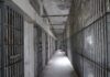 Empty prison corridor with barred cells on either side