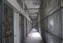 Empty prison corridor with barred cells on either side