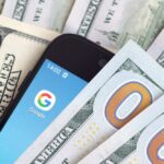 Smartphone with Google app on screen among US dollar bills