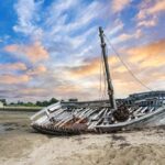 Huge Storm Unearths U.S. Ghost Ship An abandoned boat on a sandy shore during sunset