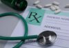 A prescription pad with a stethoscope and pills nearby