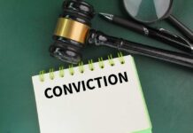 A gavel resting on a notepad with the word 'CONVICTION' written on it