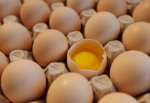 Eggs in carton one cracked revealing yolk
