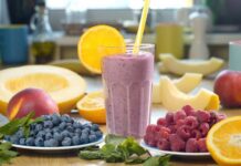 Berry smoothie in a glass with orange slice and straws