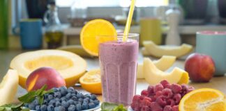 Berry smoothie in a glass with orange slice and straws