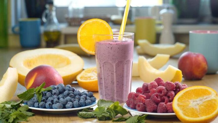 Berry smoothie in a glass with orange slice and straws