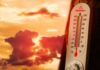 Thermometer displaying high temperature against a sunset background