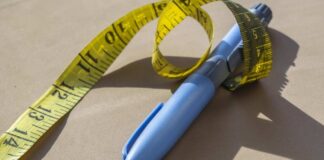 Blue pen with yellow measuring tape on a table
