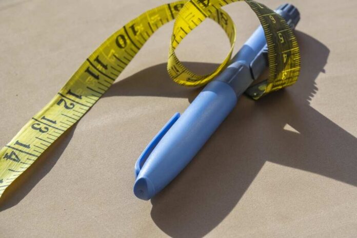Blue pen with yellow measuring tape on a table