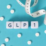 GLP-1 cubes with pills and a measuring tape on blue background