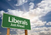 Green roadside sign against a cloudy sky