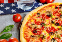Pizza with pepperoni, olives, mushrooms, and vegetables on a table