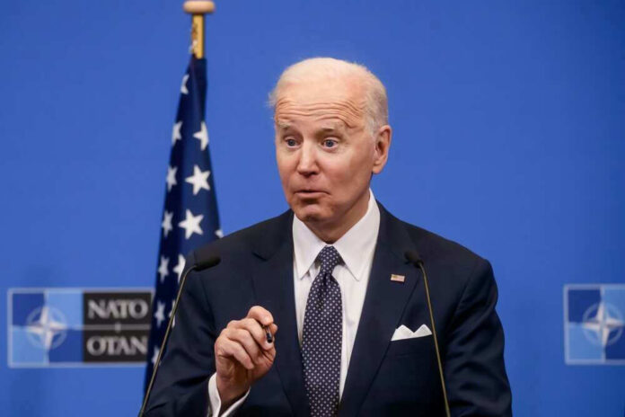 Joe Biden speaking at a podium with a blue NATO backdrop