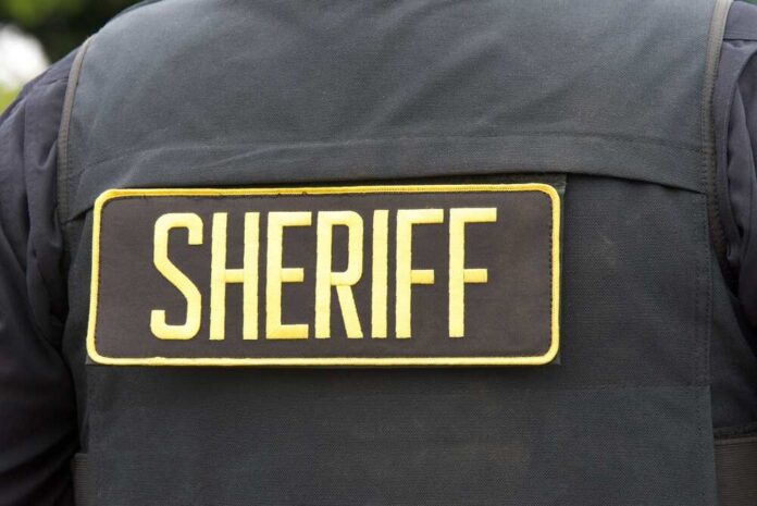 Close,Up,On,Sheriff,Letters,On,Back,Of,Flack,Jacket. Close-up of a sheriff's uniform with a badge