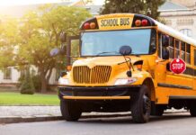 Yellow school bus parked by a campus sidewalk