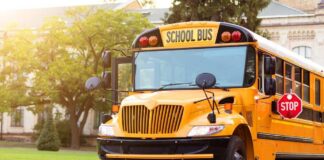 Yellow school bus parked by a campus sidewalk