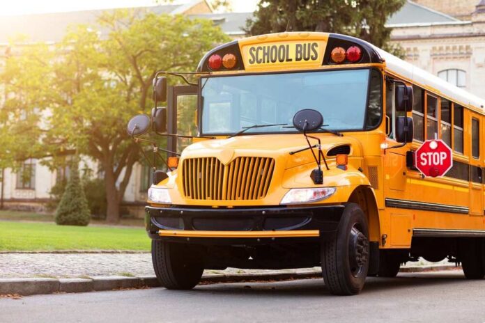 Shot,Of,Retro-styled,Yellow,School,Bus,With,Extended,Red,Stop Yellow school bus parked by a campus sidewalk