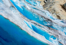 Blue glacier ice with crevasses and rocky surface