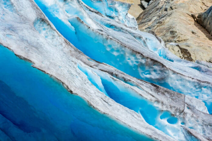 Blue glacier ice with crevasses and rocky surface
