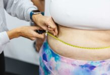 A person measuring anothers waist with a tape measure