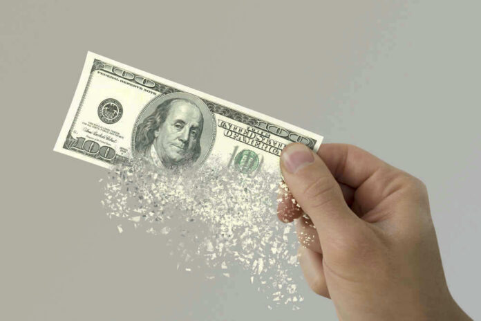 shutterstock_580278601 Hand holding a disintegrating hundred dollar bill.
