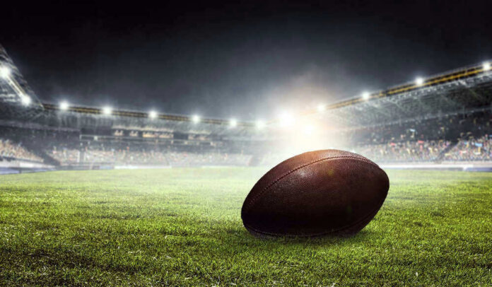 shutterstock_648227854 Football on field in illuminated stadium at night.